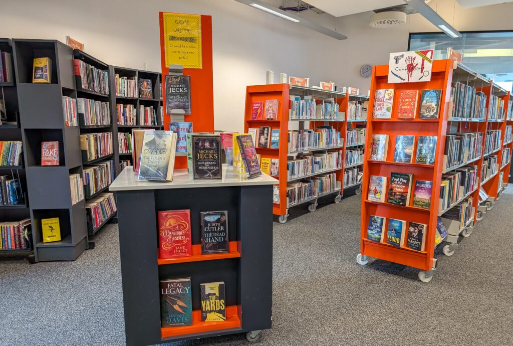 Photograph of the interior of Stockbridge Library Showing orange shelving displays full of adult fiction books.